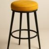 Tabouret moderne avec assise ronde jaune ocre et piètement noir en métal.